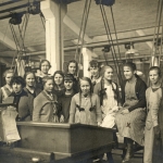 En grupp unga kvinnor och en förman står uppställda i en verkstad.