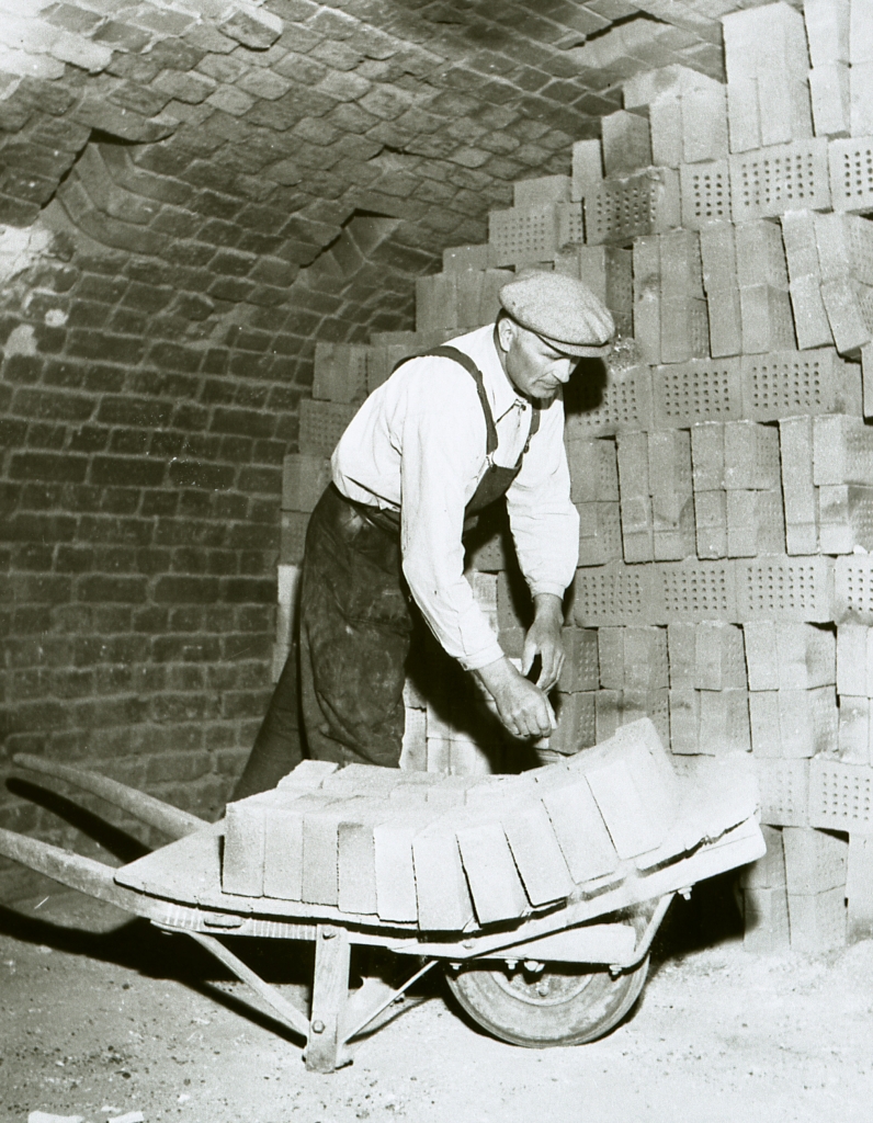 En man vid en skottkärra full av tegelstenar.