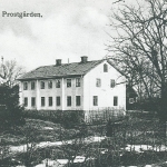 Ett svartvitt foto av en ljus tvåvåningsbyggnad .