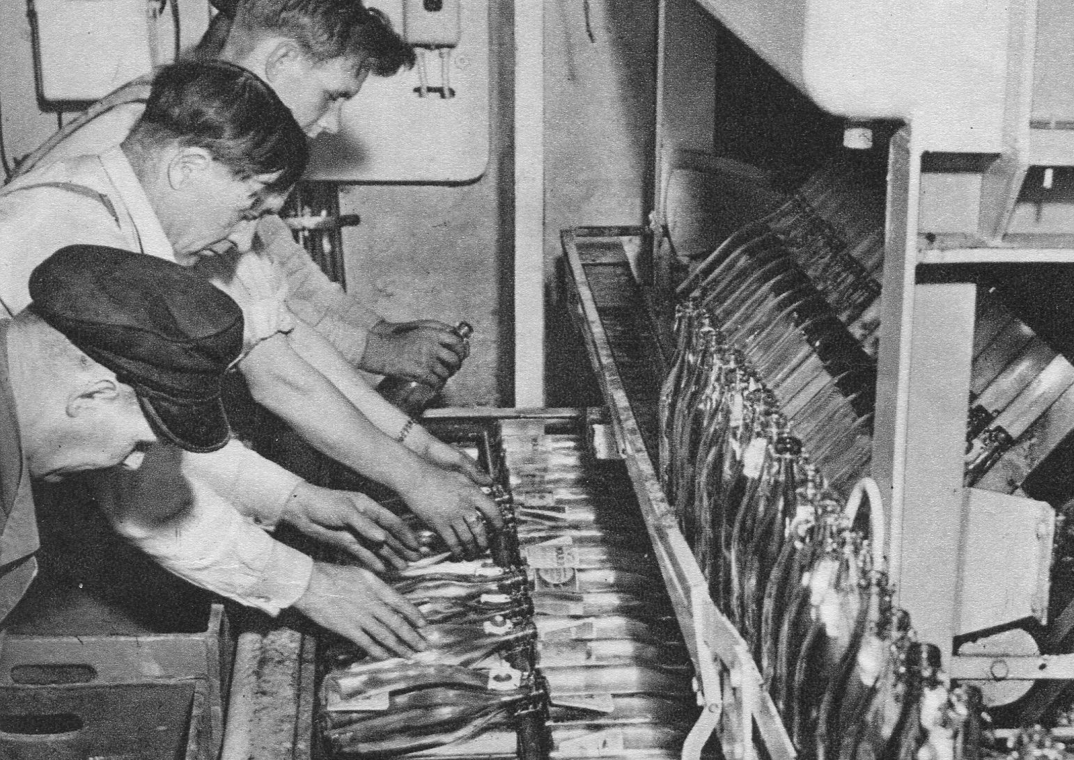 Svartvitt foto av fyra män som arbetar med flaskor vid ett löpande band.