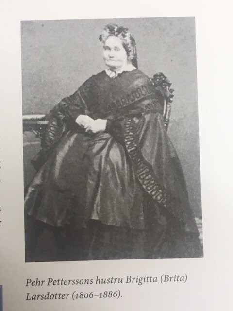 Svartvit porträtt av en äldre kvinna sittande i en stol.