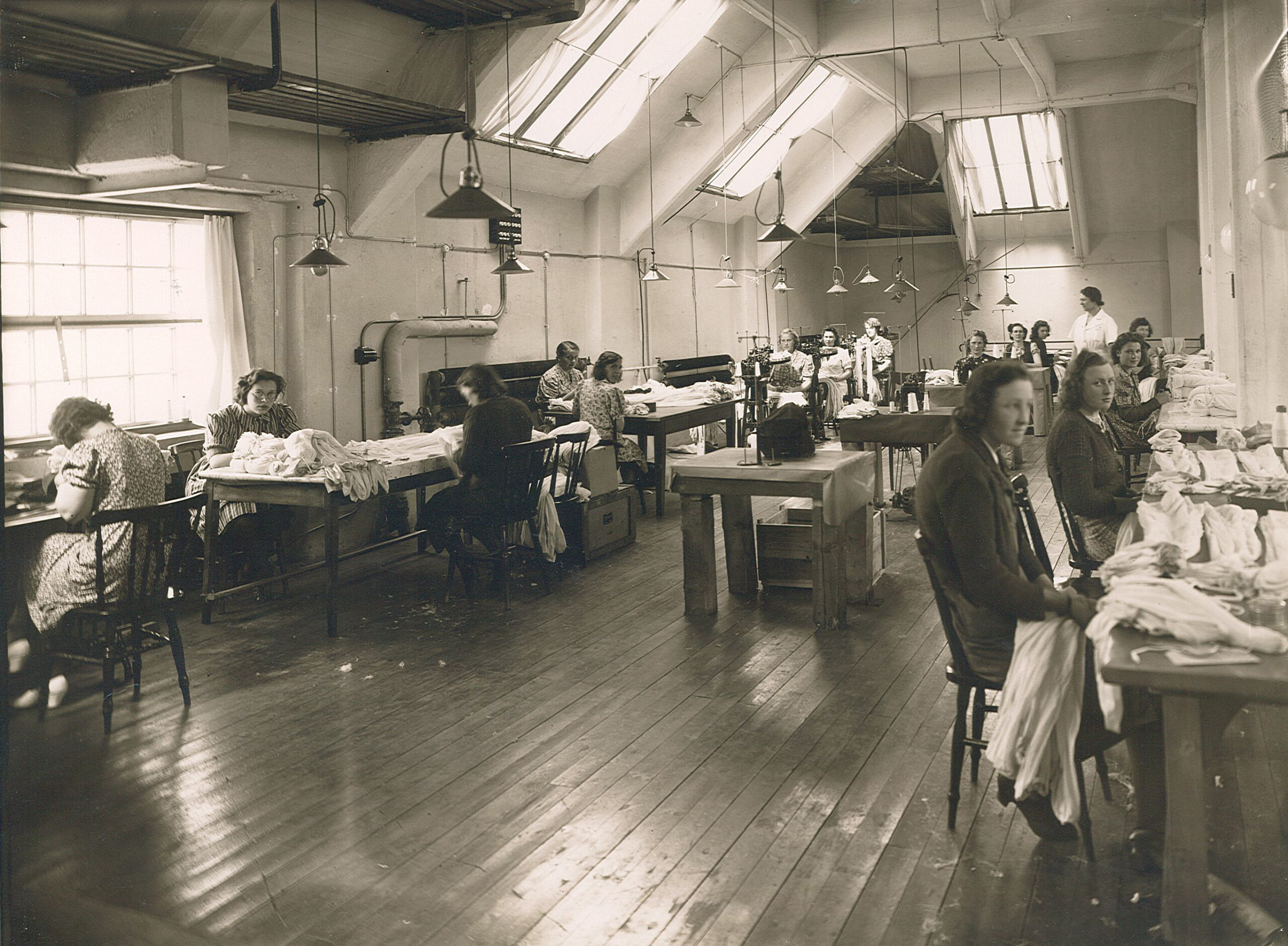 Kvinnor vid bänkar i en stor lokal.