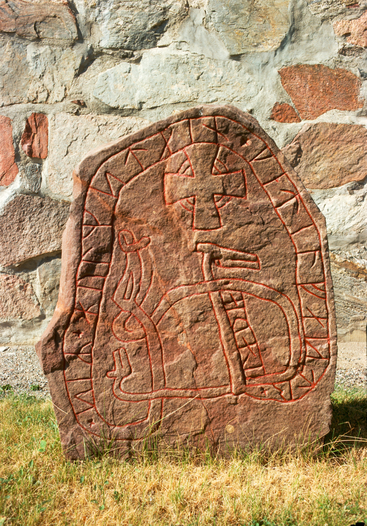 Runsten utanför Lovö kyrka, fotograferad på grön gräs i solsken