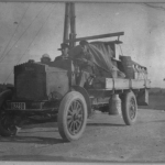 En gammal lastbil med stora mjölkkannor i metall. Några hänger från bilen.