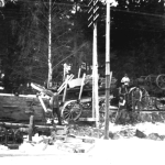 Lokomobilen står på en väg men två vagnar har tippat och en av dem ligger i diket.