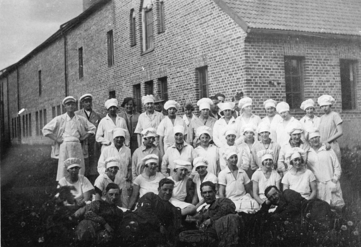 Gruppfoto av bagerianställda framför tegelbyggnad