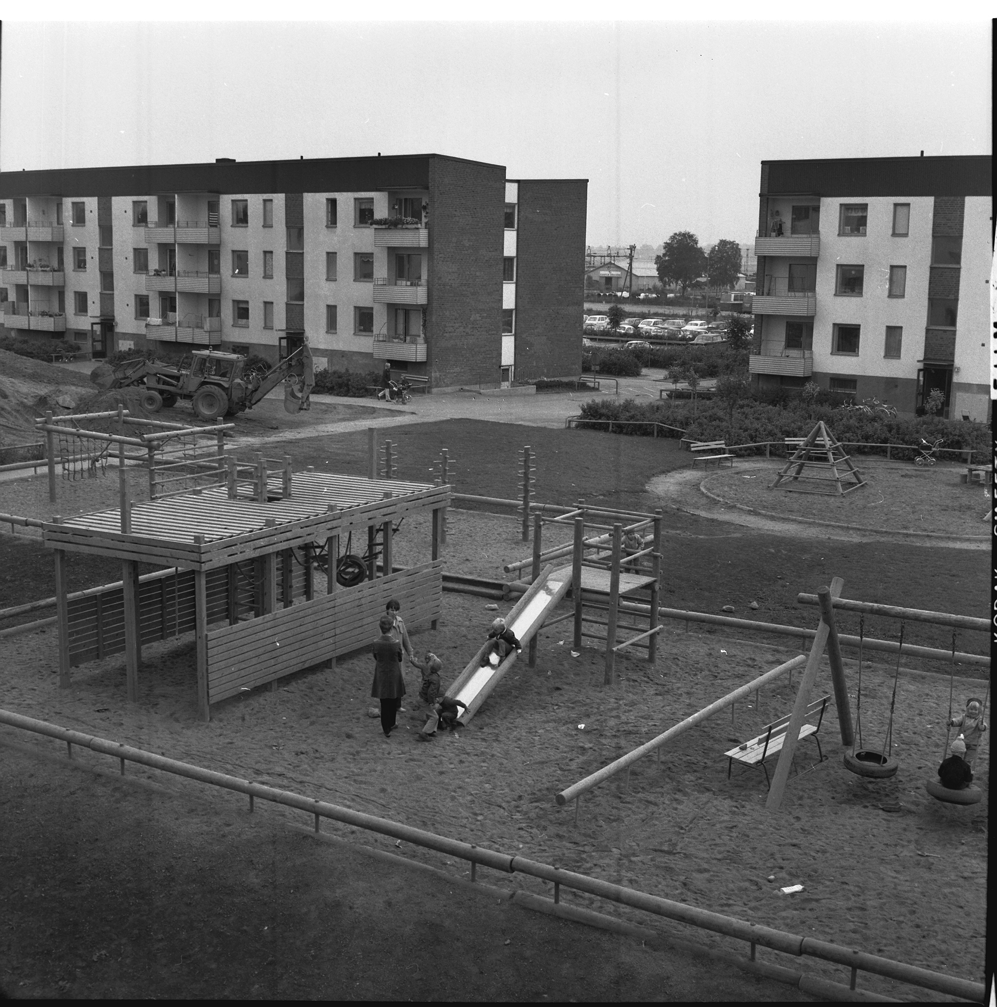 En svartvit bild av några barn och vuxna på en innergård.