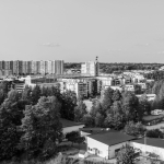 Ett svartvitt foto där det bågformatde 17-våningshuset och ett annat höghus sticker upp över horisonten. Bilden är fylld av andra längre hus. I bakgrunden syns skog.