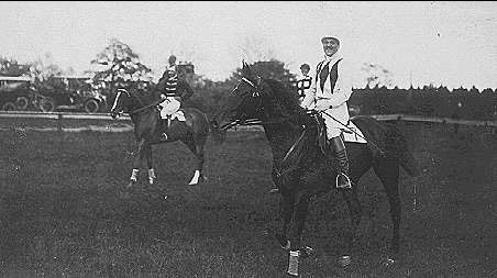 Svartvitt foto. Galopphästar och ryttare.