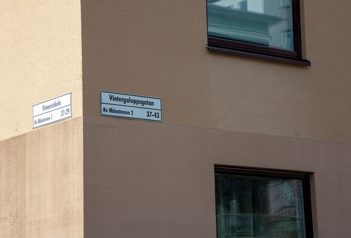 Foto. Husgavel i gul puts med gatunamn.