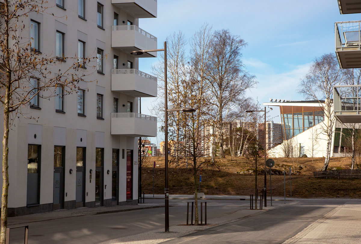 Foto. Lägenhetshus och läktarbyggnad.