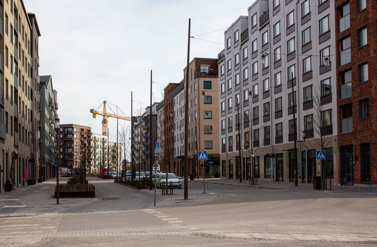 Foto. Nybyggda lägenhetshus med lyftkran i bakgrunden.