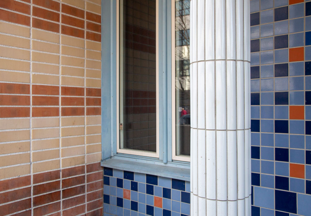 Fotografi. Närbild av fasad med kakel i olika färger och mönster.